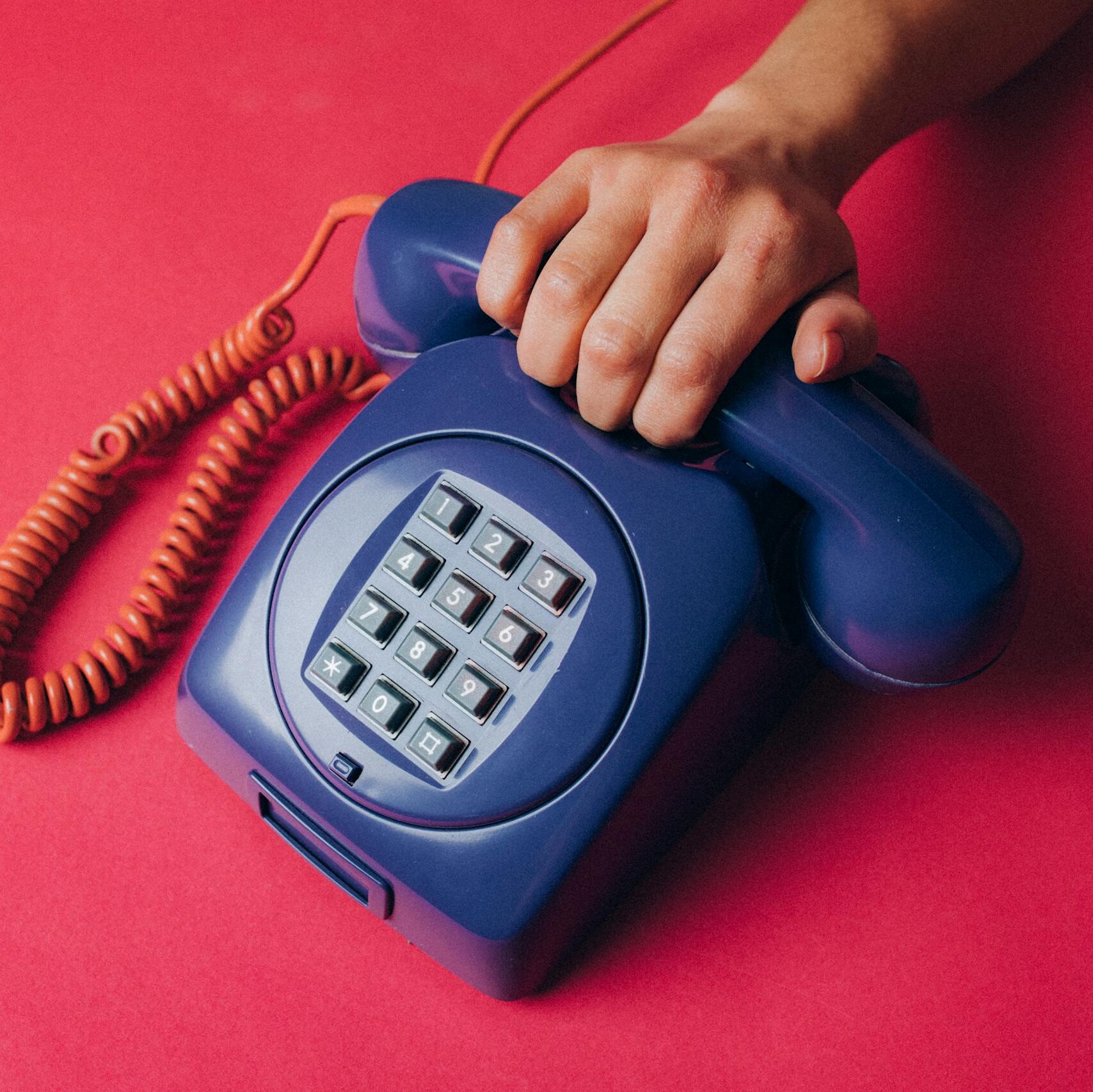 Close-up of a hand holding a vintage blue telephone, evoking nostalgia and retro vibes.